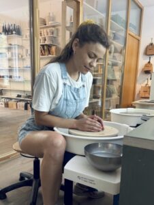 Yolanda, Leiterin des Töpferkurses bei db pottery in Zürich, sitzt an der Töpferscheibe und zentriert Ton.