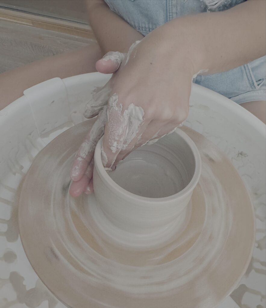 Großaufnahme einer Person an der Töpferscheibe, die die Formen einer Wand formt.