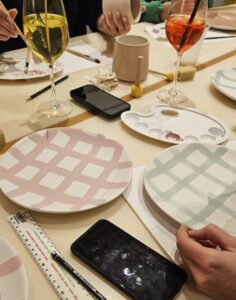 Keramik bemalen mit Streifen im Kreuzmuster: Teller mit rosa und grünen Linien, die sich überkreuzen und ein modernes Karomuster erzeugen, gestaltet im kreativen Workshop-Setting (25hours hotel Langstrasse).