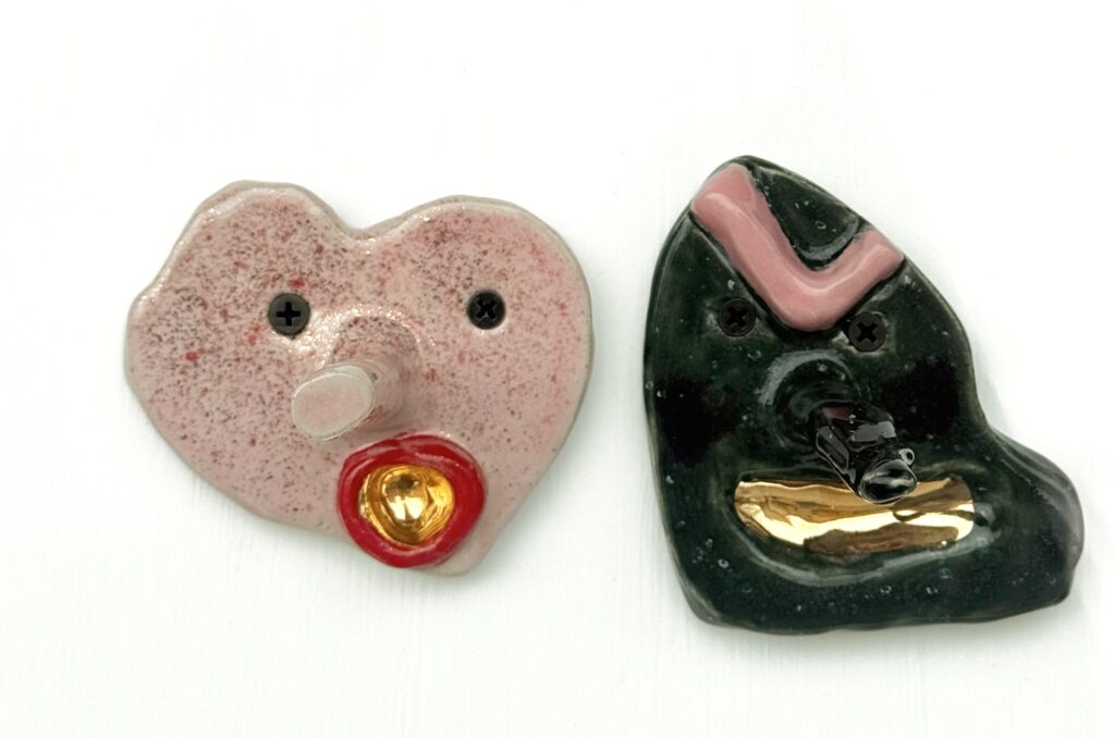 Children's pottery featuring hand built ceramic monster wall hooks by young maker Moritz Popp, shown in close up with bold colors and expressive faces.