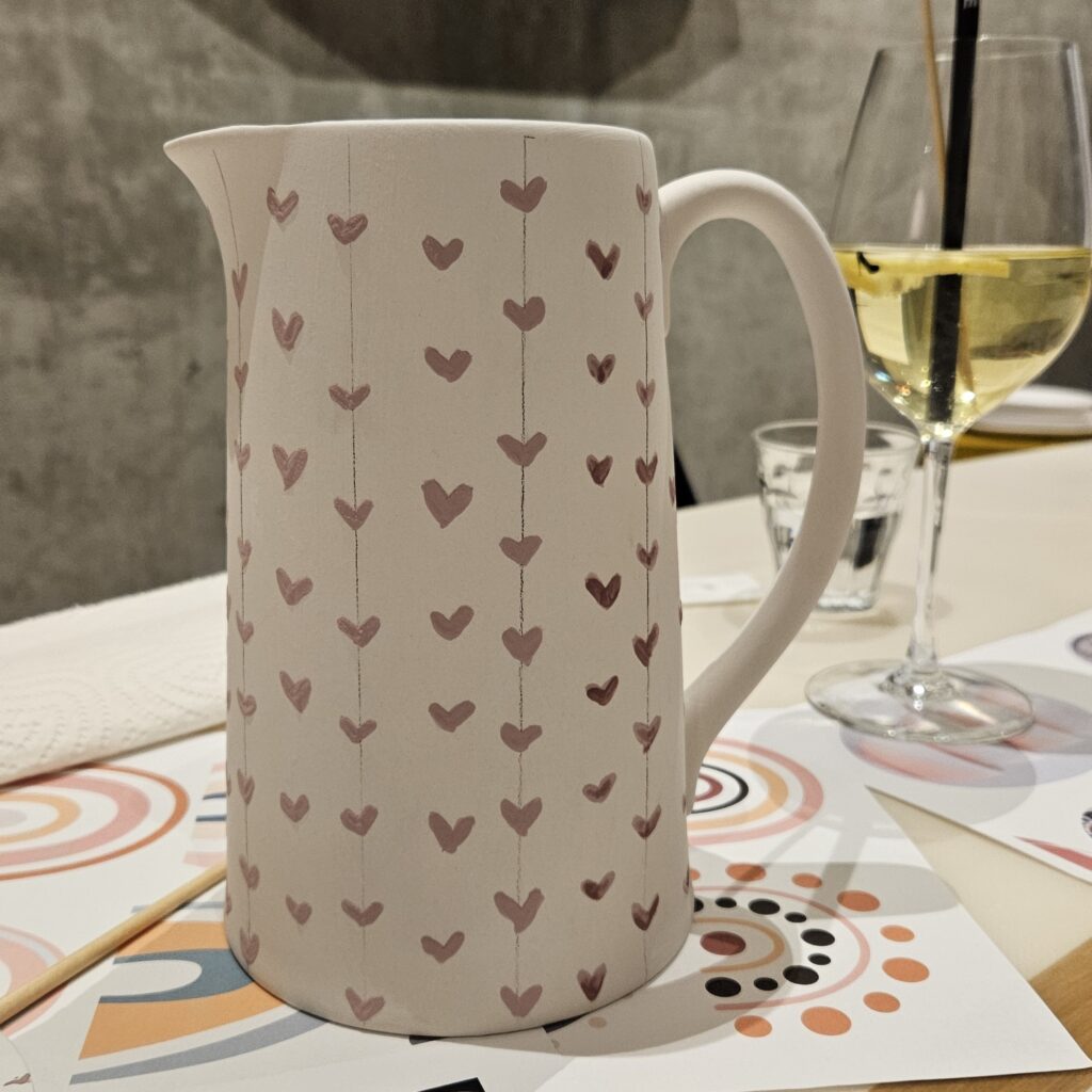 Keramik bemalen mit zartem Muster: Hohe Kanne mit handgemalten kleinen Herzmotiven in Reihen, gestaltet im filigranen Dainty-Design-Stil.