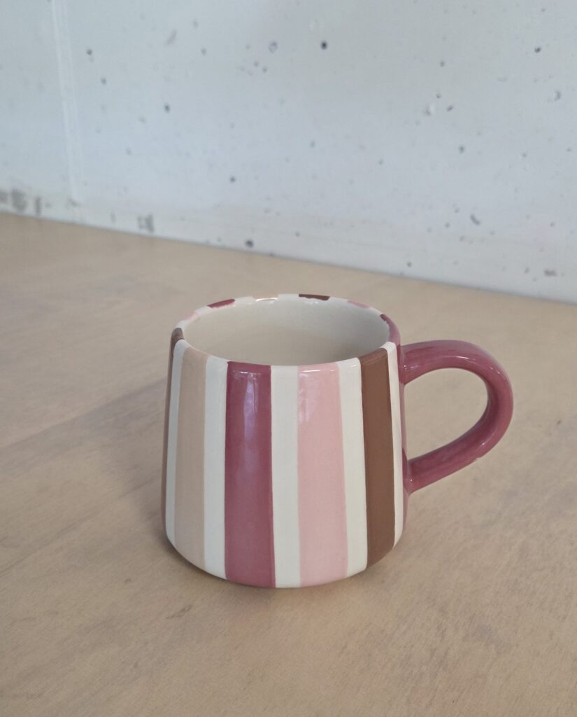 Keramik bemalen mit Klebeband für saubere Linien: Handbemalte Tasse mit gleichmäßigen vertikalen Streifen in Rosa-, Creme- und Brauntönen im klaren, modernen Design.