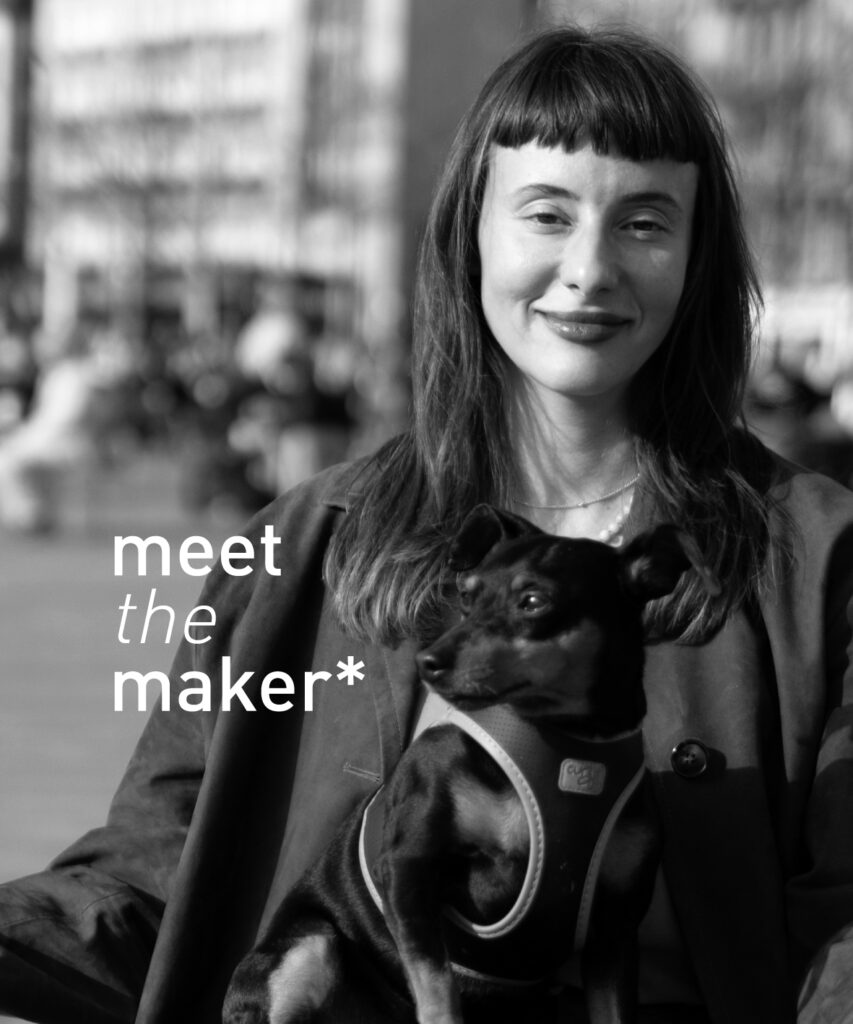 Black and white portrait of ceramic maker and db pottery member Laura Hasenöhrl holding a small dog, with 'meet the maker*' text overlay