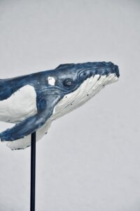 Nahaufnahme des Kopfes eines blau-weissen Keramik-Buckelwals, mit Auge und Maul im Detail.
