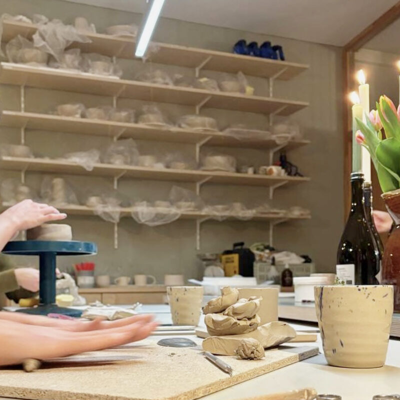 workshop room table with clay and tools on the table and hands of participants doing a cozy pottery handbuilding workshop at db pottery studio