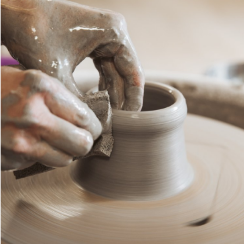 The hands of a participant who is taking a pottery wheel course at db pottery studio in Zurich. The persons hands is working on the form and pulling up the walls of their vessel.